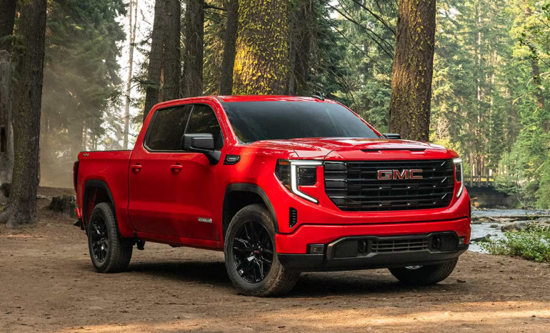 Red 2026 GMC Sierra 1500 parked in the middle of a forest.